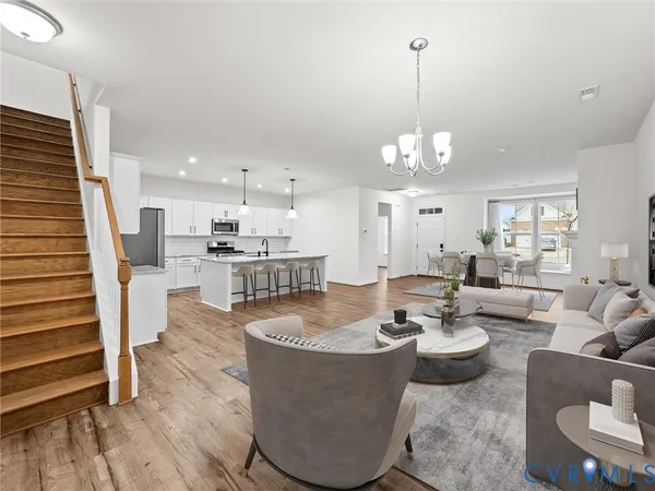 a living room with furniture kitchen view and a chandelier