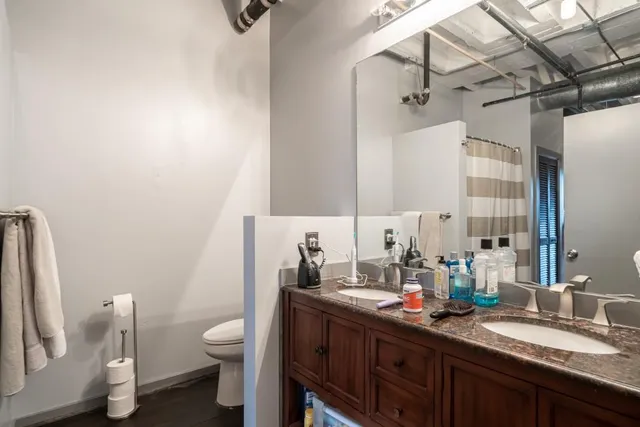 a bathroom with a granite countertop sink a toilet and a mirror