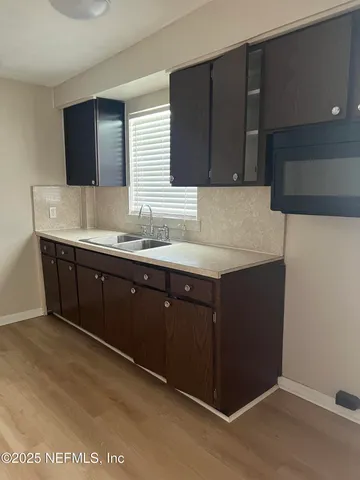 a kitchen with stainless steel appliances wooden floor and view living room