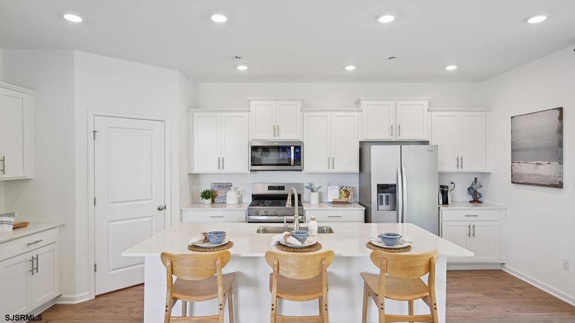 401 Scotty Boulevard, Unit 1106 Rio Grande, NJ 08242 - Photo 20 of 46 a kitchen with stainless steel appliances kitchen island granite countertop a dining table and chairs