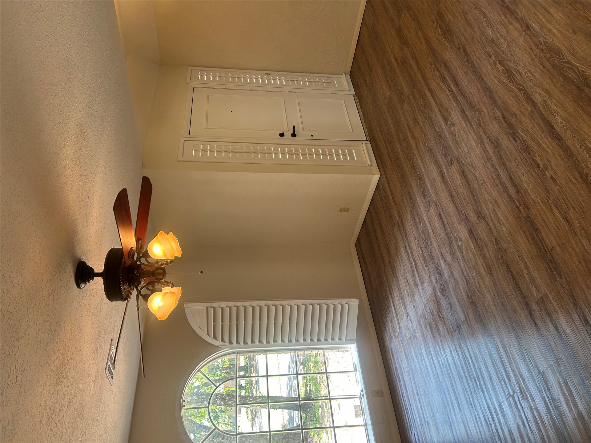 2913 Springdale Lane Duncan, OK 73533 - Photo 19 of 32 Wood-finish flooring throughout, ceiling fan with integrated lighting, arched window with white shutters, and white paneled entry door with sidelights
