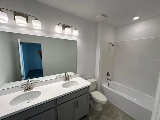 a bathroom with a double vanity sink toilet and a mirror
