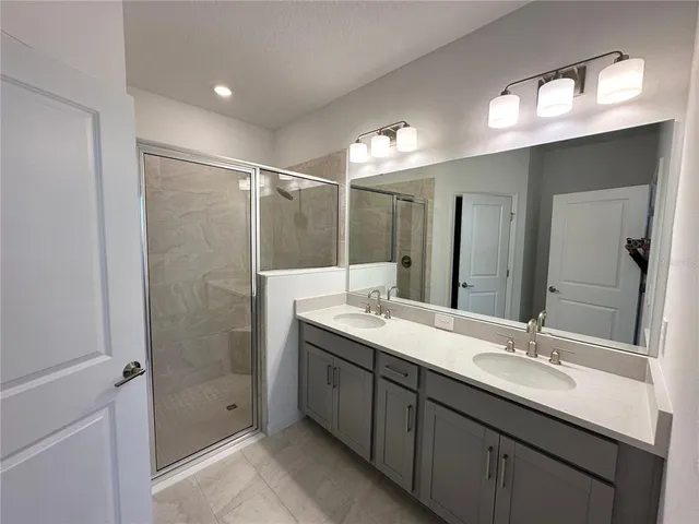 a bathroom with a double vanity sink mirror and shower