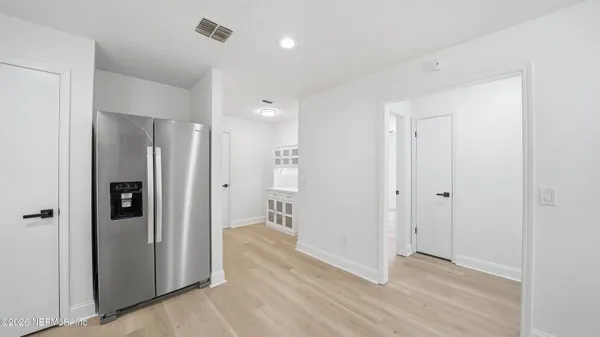 a view of a hallway with wooden floor and a refrigerator