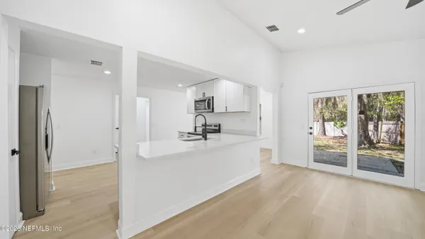 a large white kitchen with kitchen island a sink stainless steel appliances and cabinets