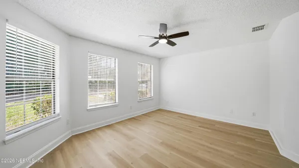 a view of an empty room with a window and wooden floor
