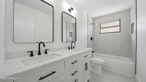 a bathroom with a double vanity sink a toilet and a bathtub