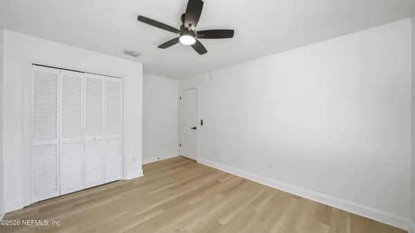 an empty room with a ceiling fan and wooden floor