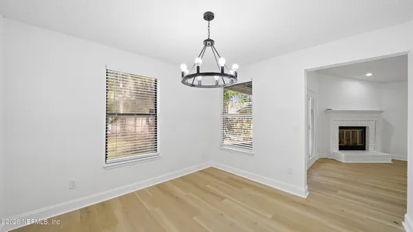 an empty room with wooden floor fireplace and windows