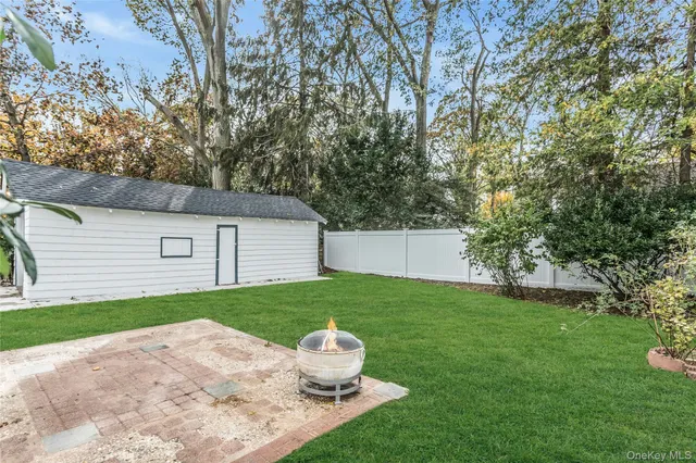 a backyard of a house with table and chairs plants and large tree
