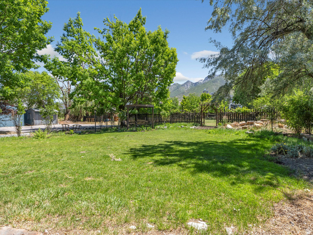 12825 South Fort Street Draper, UT 84020 - Photo 35 of 52 Expansive grassy yard area featuring mature trees, a wood privacy fence, and mountain scenery
