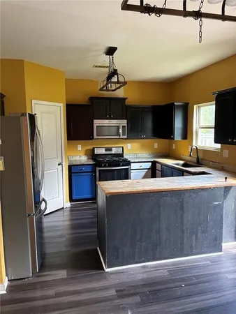 an empty room with wooden floor chandelier fan and windows
