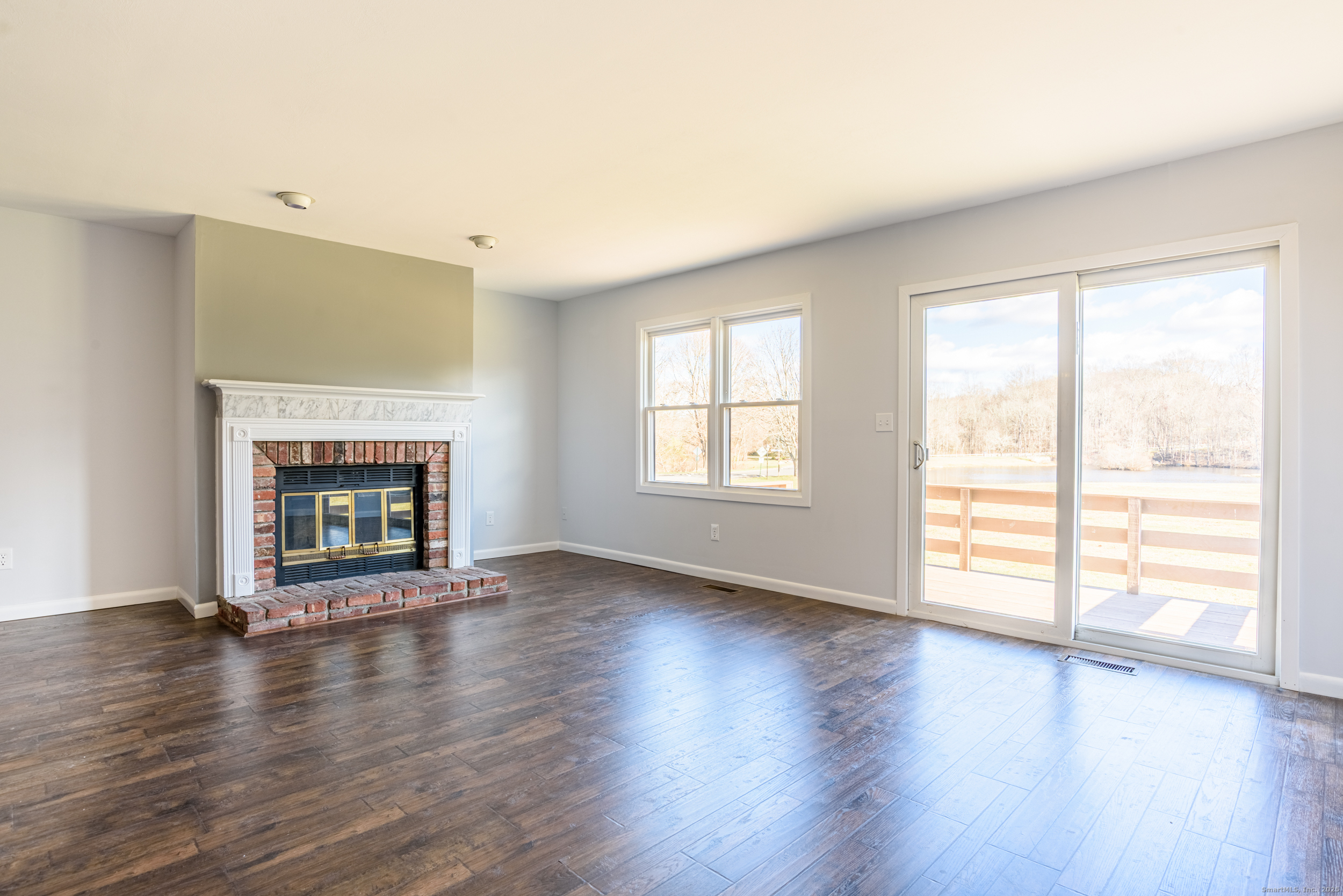 84 Stillmeadow Circle, Unit 84 Monroe, CT 06468 - Photo 9 of 20 an empty room with wooden floor fireplace and windows