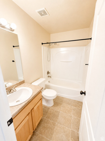14767 Invergarry Court Draper, UT 84020 - Photo 13 of 18 Bathroom featuring a light wood-finish vanity with an integrated sink, a full bathtub with a shower, and neutral-toned square tile flooring