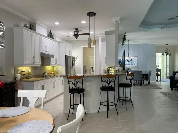 a kitchen with stainless steel appliances kitchen island granite countertop a dining table chairs and a refrigerator