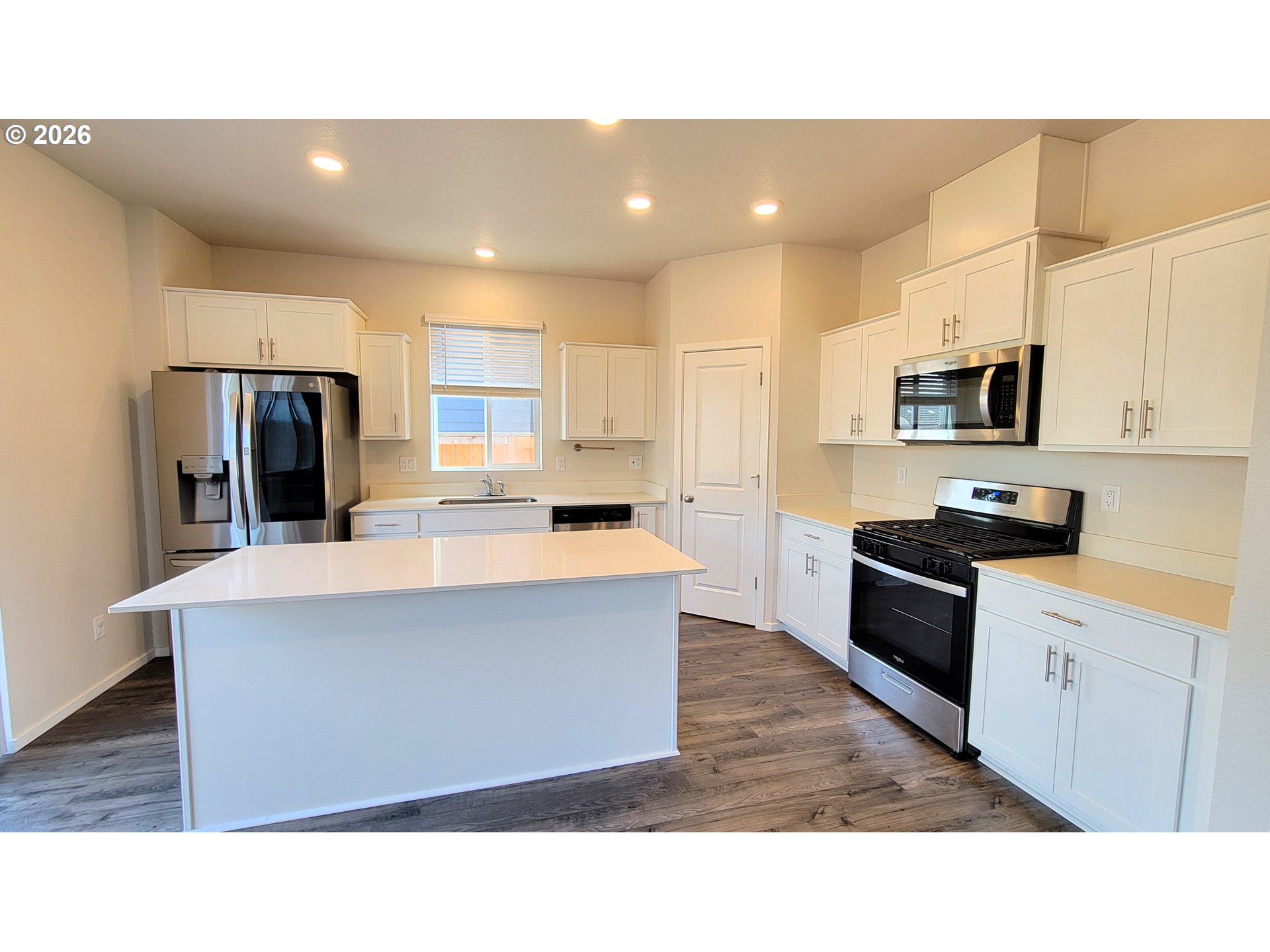 2960 V Street Springfield, OR 97477 - Photo 4 of 27 a open kitchen with stainless steel appliances kitchen island granite countertop a stove a sink a refrigerator and white cabinets with wooden floor