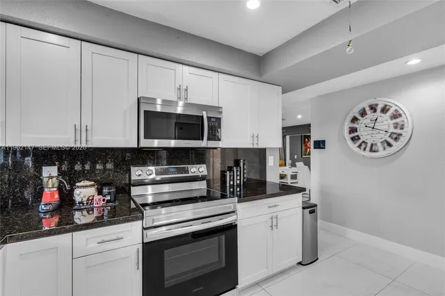 a kitchen with stainless steel appliances granite countertop white cabinets a sink and dishwasher