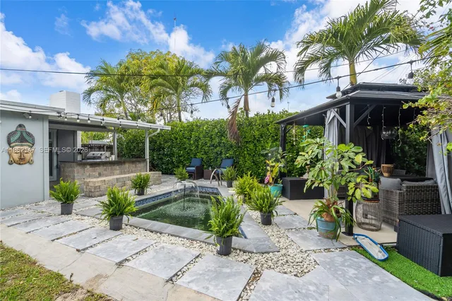 a view of a patio with table and chairs under an umbrella with potted plants