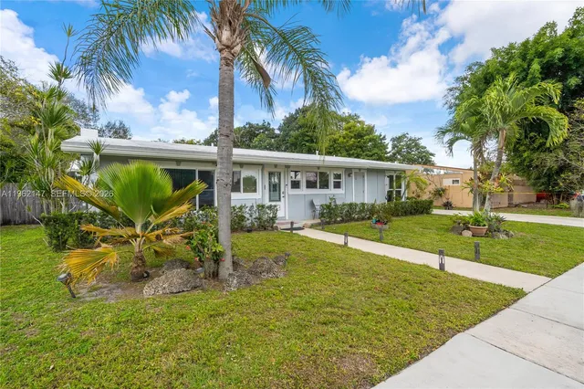 front view of house with a yard and potted plants