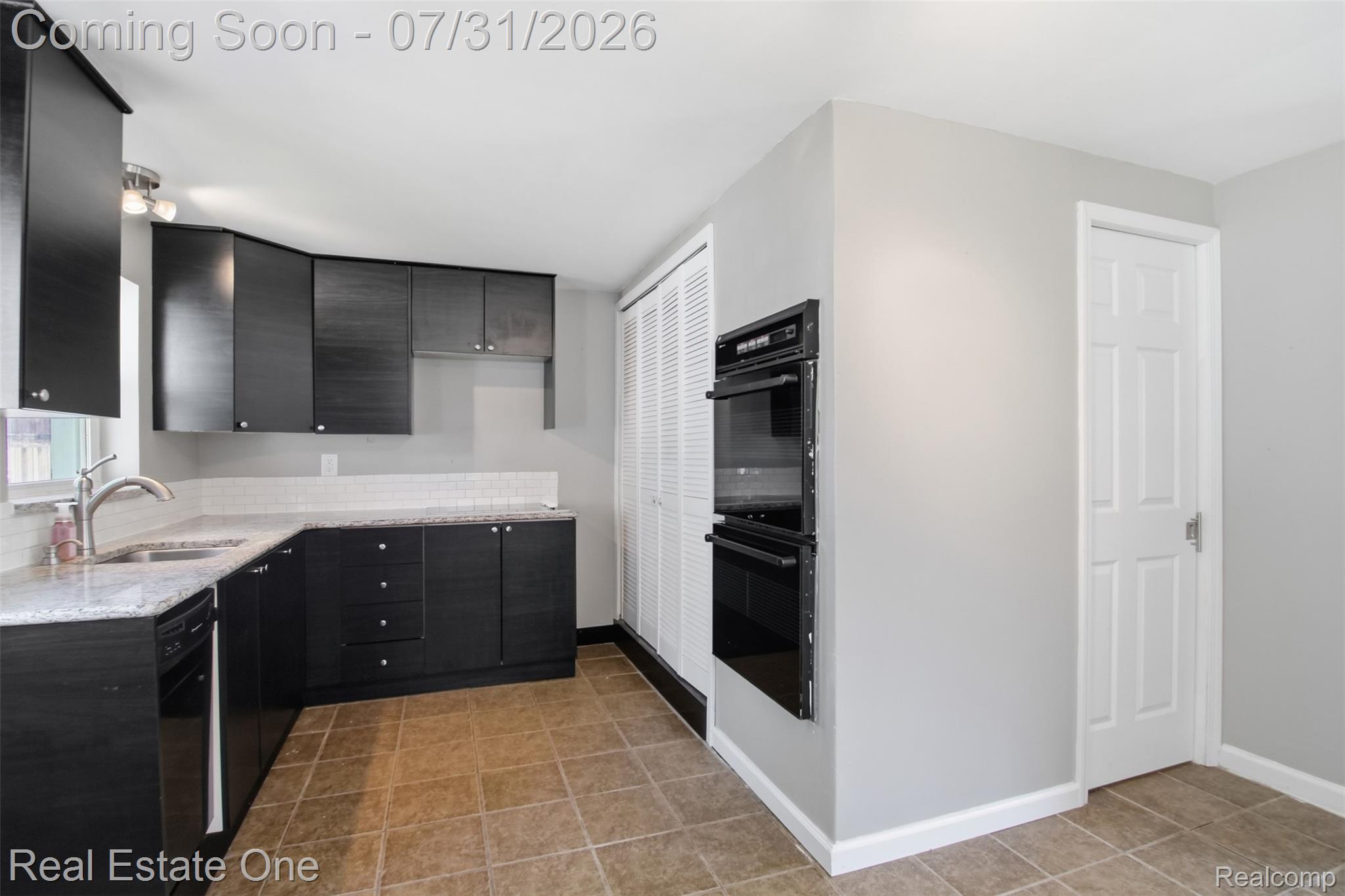 1615 South Commerce Road Walled Lake, MI 48390 - Photo 18 of 34 Kitchen featuring dark cabinetry, light-toned countertops, a white subway tile backsplash, and a built-in double oven