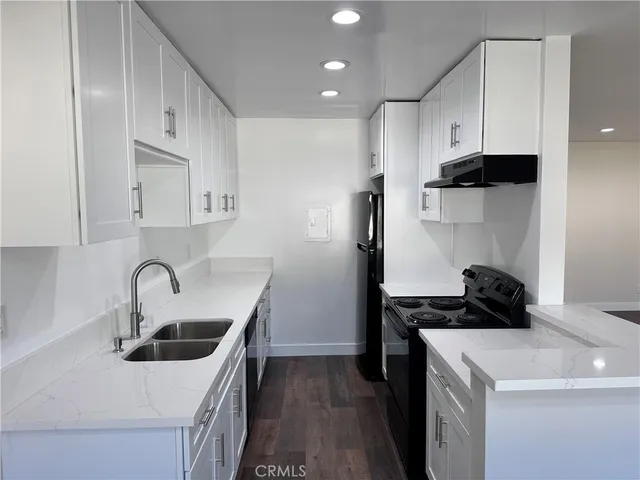 a kitchen with stainless steel appliances a sink a stove and a refrigerator with wooden floor