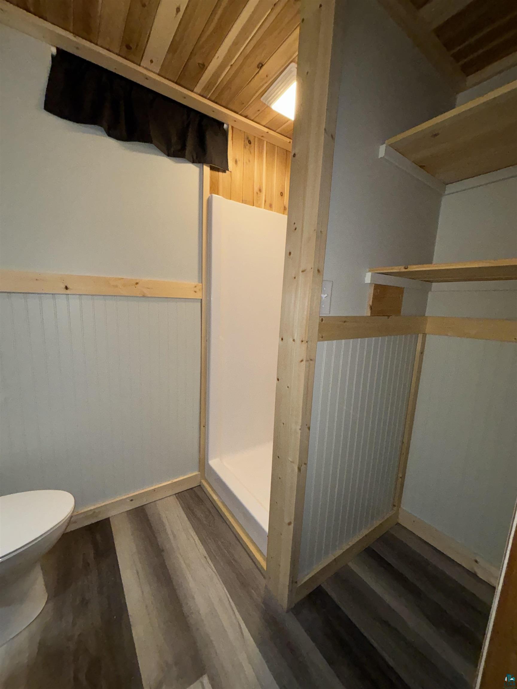 444 Fernberg Road, Unit 11 Ely, MN 55731 - Photo 18 of 19 Bathroom featuring a white shower stall, wood-finish flooring, and a natural wood plank ceiling