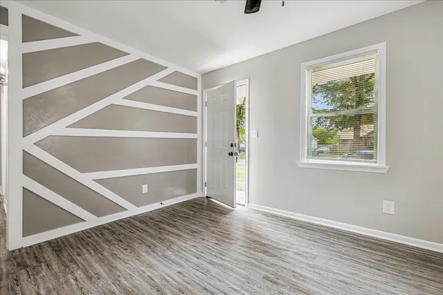 a view of an empty room with a window and wooden floor