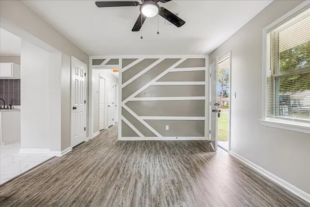 a view of an empty room with a window and wooden floor