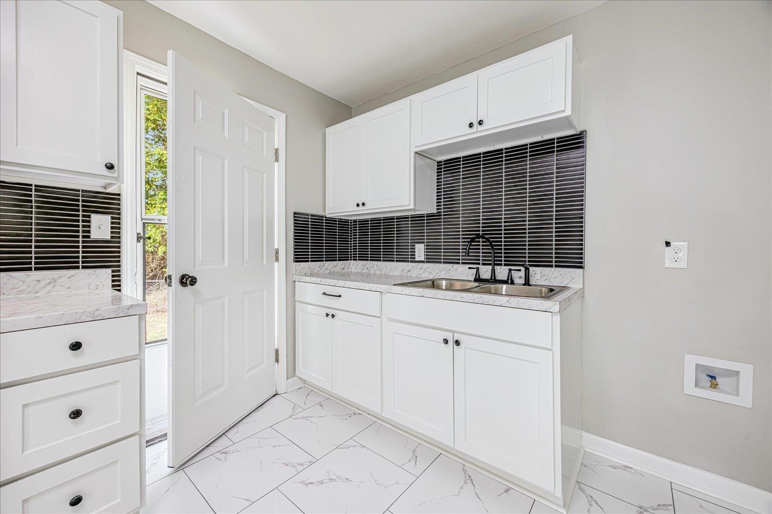 179 Harris Cove Collierville, TN 38017 - Photo 9 of 25 Kitchen featuring white cabinetry, light marble finish flooring, decorative backsplash, and light stone countertops