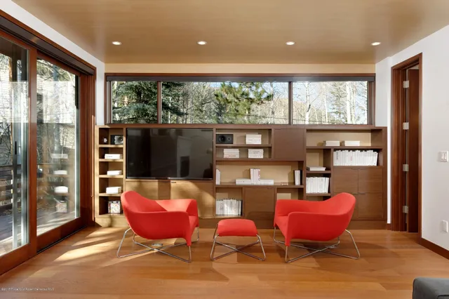 a living room with furniture a flat screen tv and floor to ceiling window