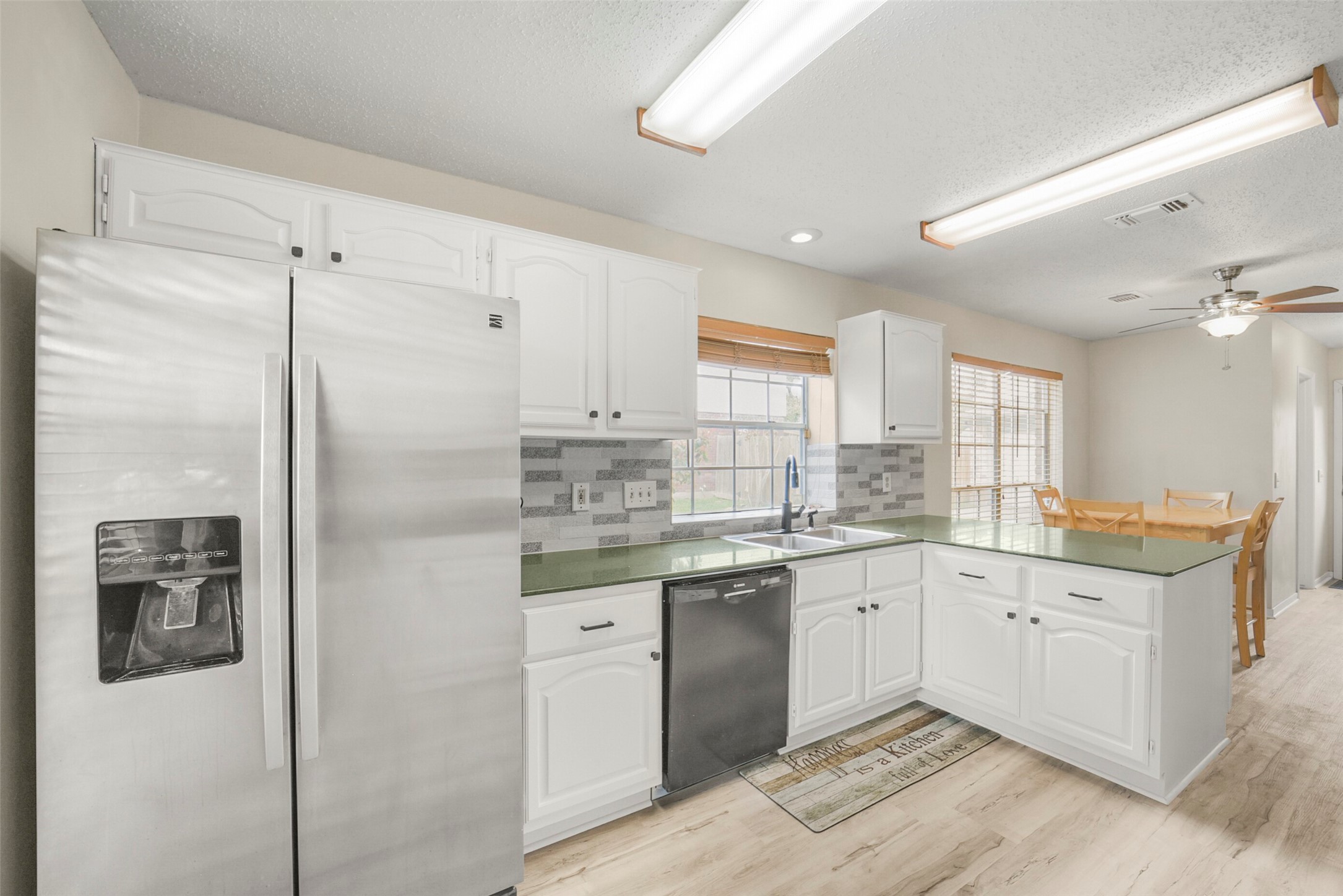 10410 Dude Road Houston, TX 77064 - Photo 11 of 45 Bright kitchen with modern stainless steel appliances, white cabinetry, and a stylish backsplash. Features a spacious layout with a dining area and ample natural light from large windows.