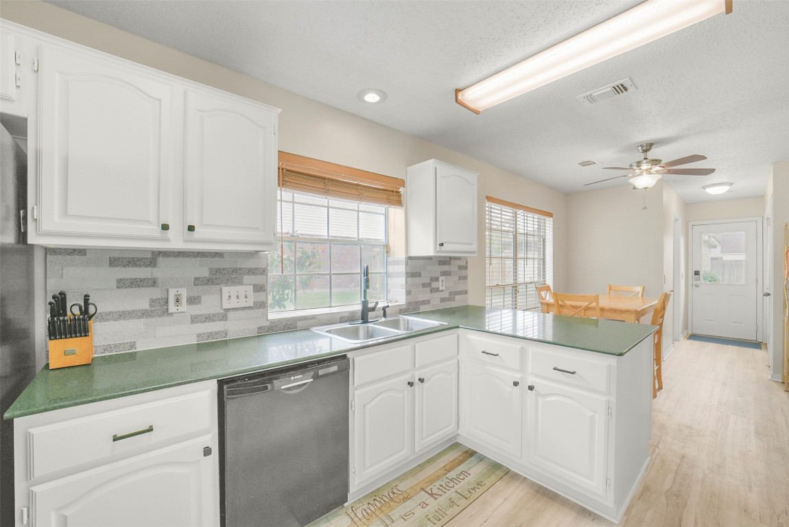 10410 Dude Road Houston, TX 77064 - Photo 12 of 45 Bright kitchen with modern finishes, featuring white cabinets, green countertops, and a tile backsplash. Includes stainless steel appliances, a spacious dining area, and ample natural light from large windows.
