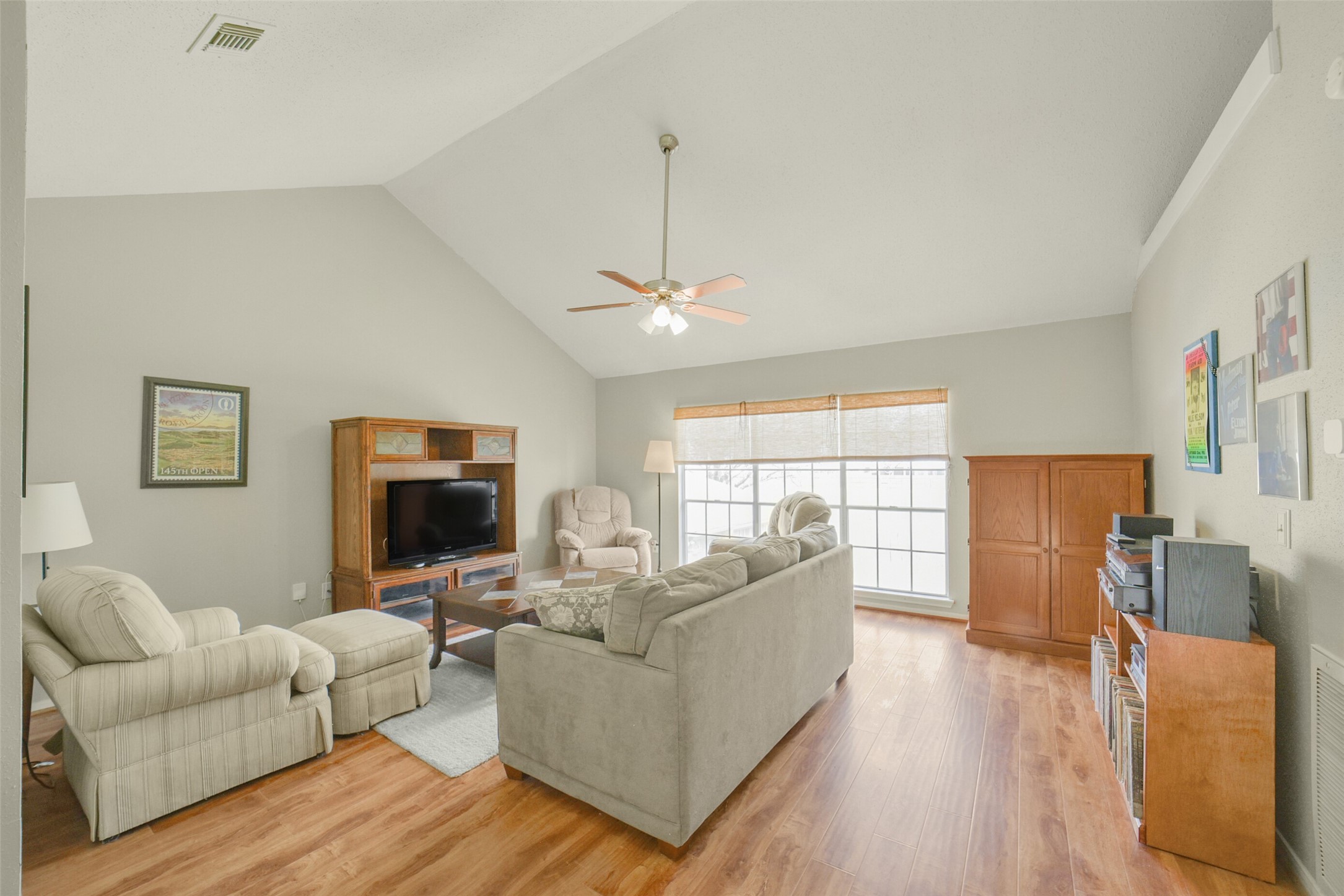 10410 Dude Road Houston, TX 77064 - Photo 24 of 45 Bright living room with high ceilings and wood flooring, featuring comfortable seating, a ceiling fan, and large windows for natural light.