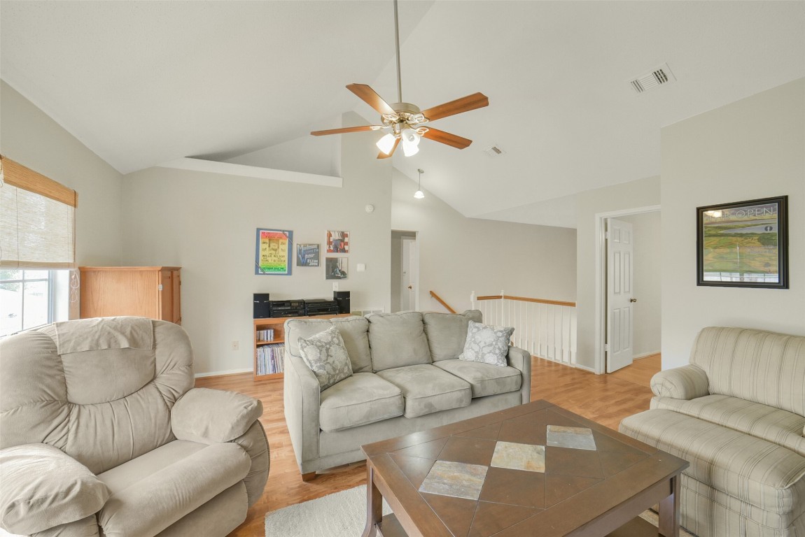 10410 Dude Road Houston, TX 77064 - Photo 26 of 45 This cozy living room features vaulted ceilings, neutral walls, and warm wood flooring. It includes comfortable seating, a ceiling fan for air circulation, and ample natural light from a large window. The space is perfect for relaxation and entertaining.