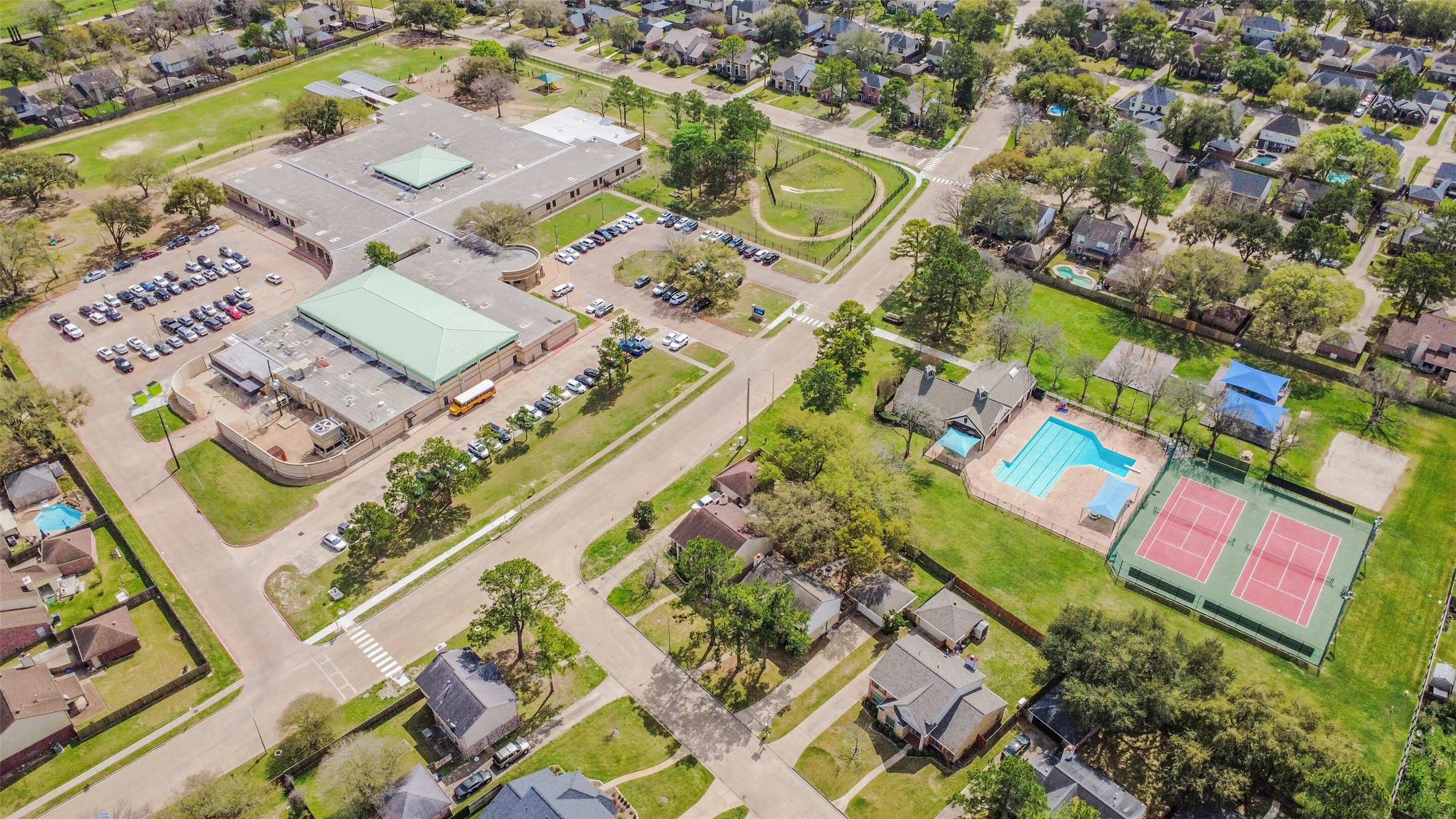 10410 Dude Road Houston, TX 77064 - Photo 39 of 45 This aerial photo showcases a suburban neighborhood with a large community center, parking area, and sports facilities including a pool and tennis courts. The surrounding area features tree-lined streets and well-maintained homes, offering a family-friendly environment.