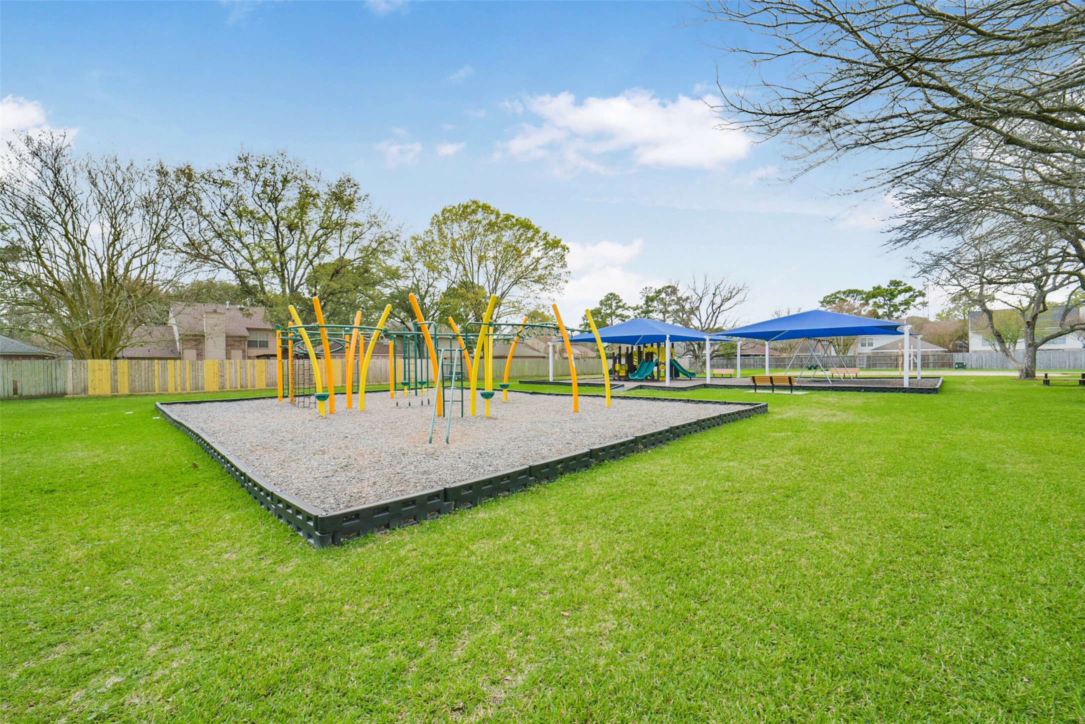 10410 Dude Road Houston, TX 77064 - Photo 40 of 45 A spacious, well-maintained park with a modern playground featuring climbing structures and swings, set on lush green grass with shade structures, perfect for families.