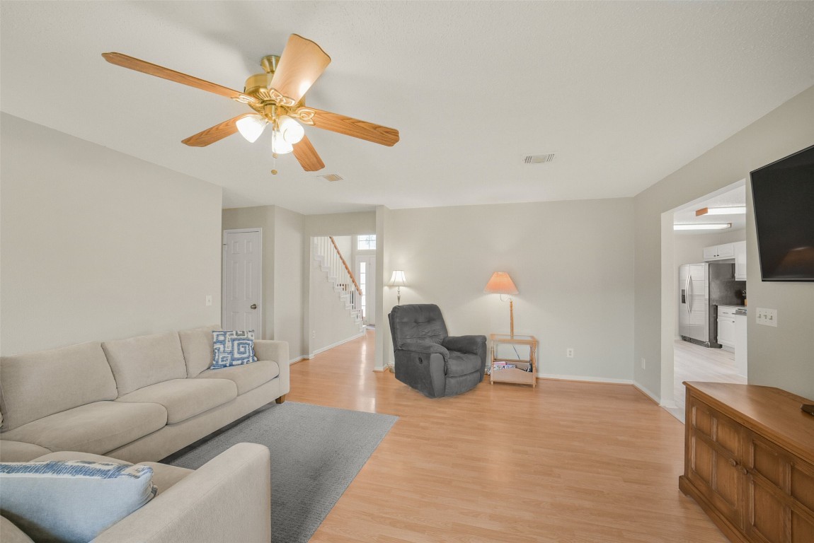 10410 Dude Road Houston, TX 77064 - Photo 6 of 45 Bright and spacious living room with light hardwood floors, neutral walls, and ceiling fan. Features comfortable seating, a large window, and open access to the kitchen. Perfect for relaxation and entertaining.