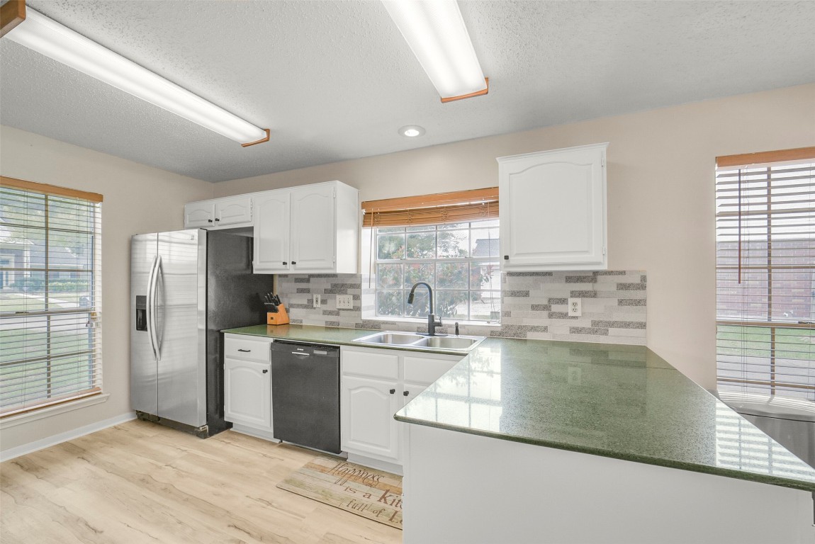 10410 Dude Road Houston, TX 77064 - Photo 8 of 45 Bright kitchen featuring stainless steel appliances, white cabinetry, and ample natural light from large windows. The room has a modern backsplash and sleek countertops, creating a welcoming and functional space.