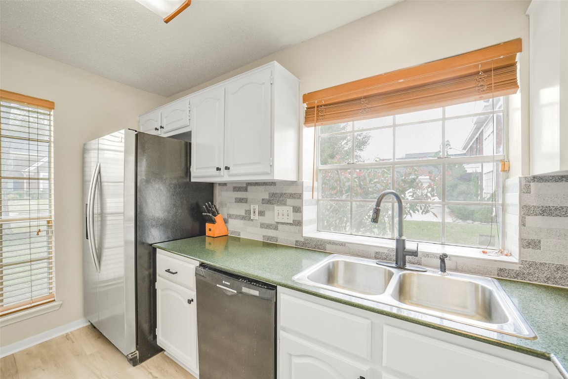 10410 Dude Road Houston, TX 77064 - Photo 10 of 45 Bright kitchen with large window, modern stainless steel appliances, and green countertops. Features white cabinetry and a double sink, creating a clean and inviting space.