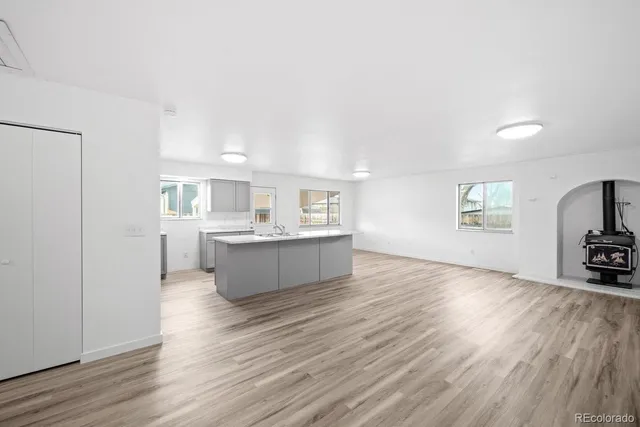 a large white kitchen with cabinets wooden floor and a sink