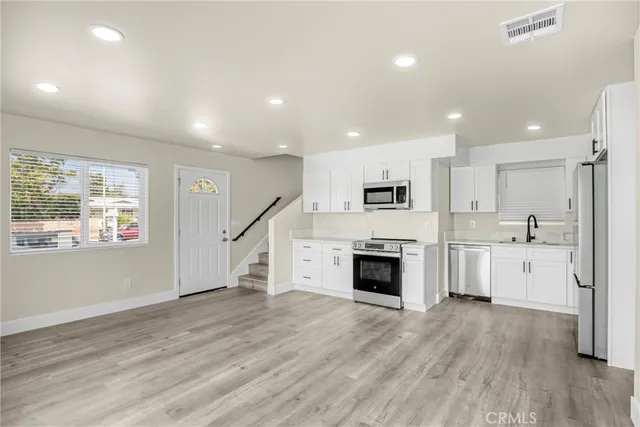 a large kitchen with cabinets wooden floor stainless steel appliances and a window