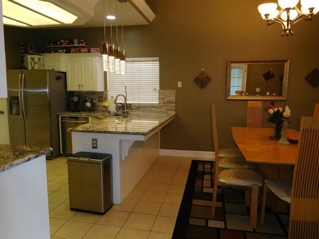a kitchen with sink a refrigerator a microwave oven and a dining table with wooden floor