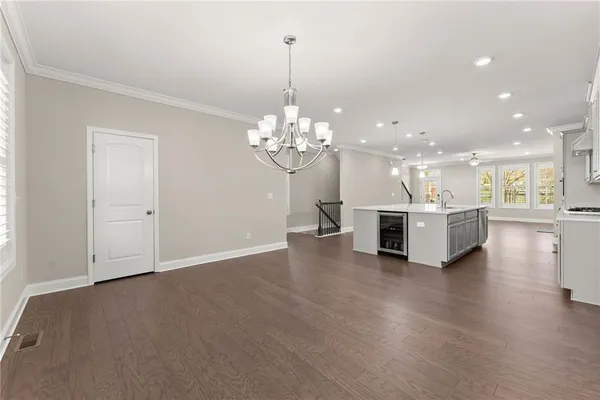 a view of an empty room with chandelier and wooden floor