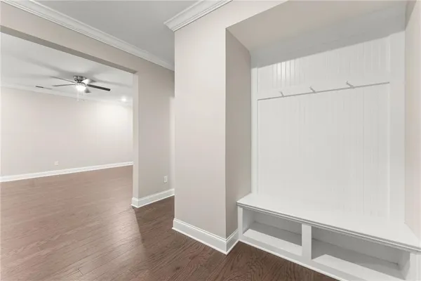 an empty room with wooden floor a ceiling fan and windows