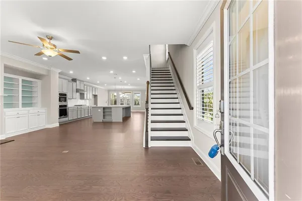 a view of an empty room with wooden floor and a kitchen