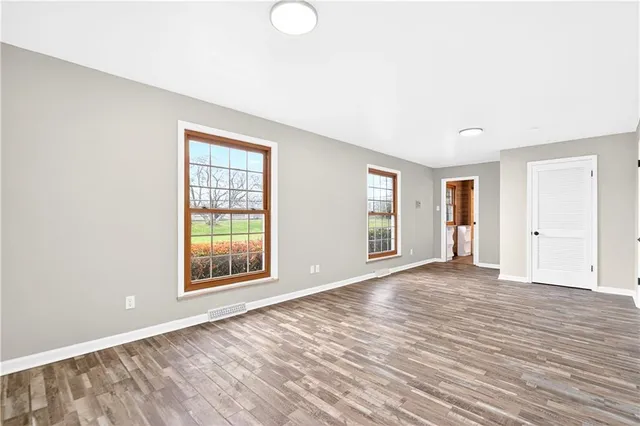 a view of an empty room with wooden floor and a window