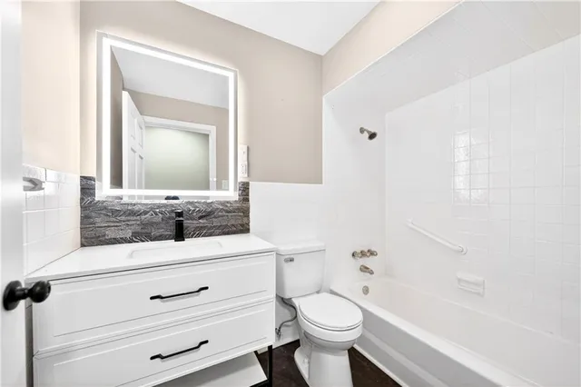 a bathroom with a toilet a sink a mirror a bathtub and vanity