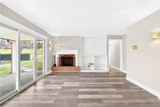 a view of empty room with wooden floor and fireplace