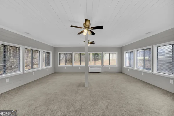 a view of a big room with wooden floor a ceiling fan and windows