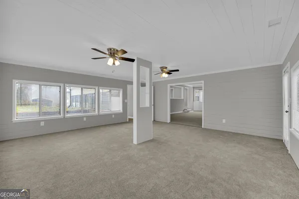 an empty room with fan and windows